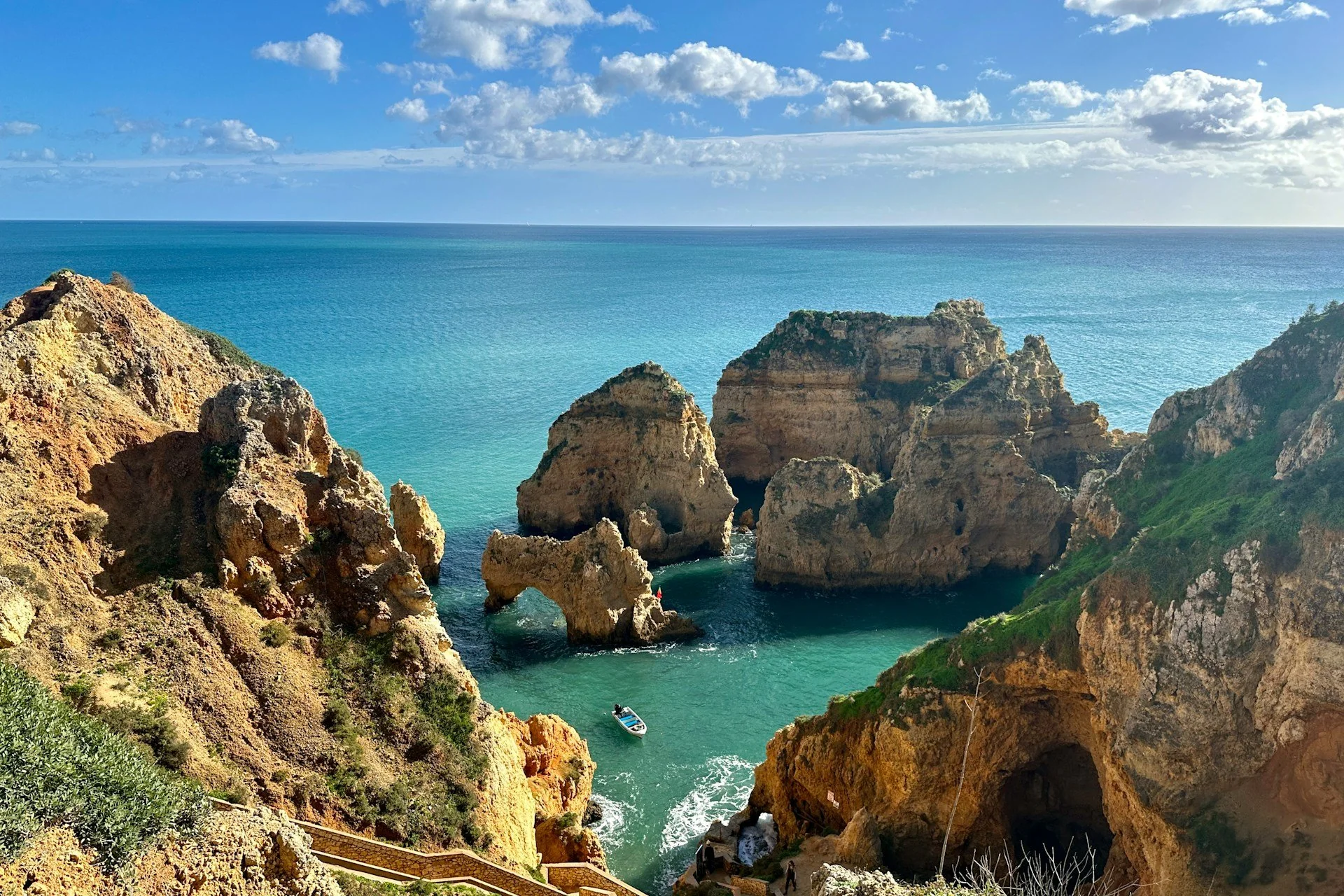 Falaises ocre et plage de sable blond de l'Algarve baignées par l'Atlantique, avec grottes marines au coucher du soleil