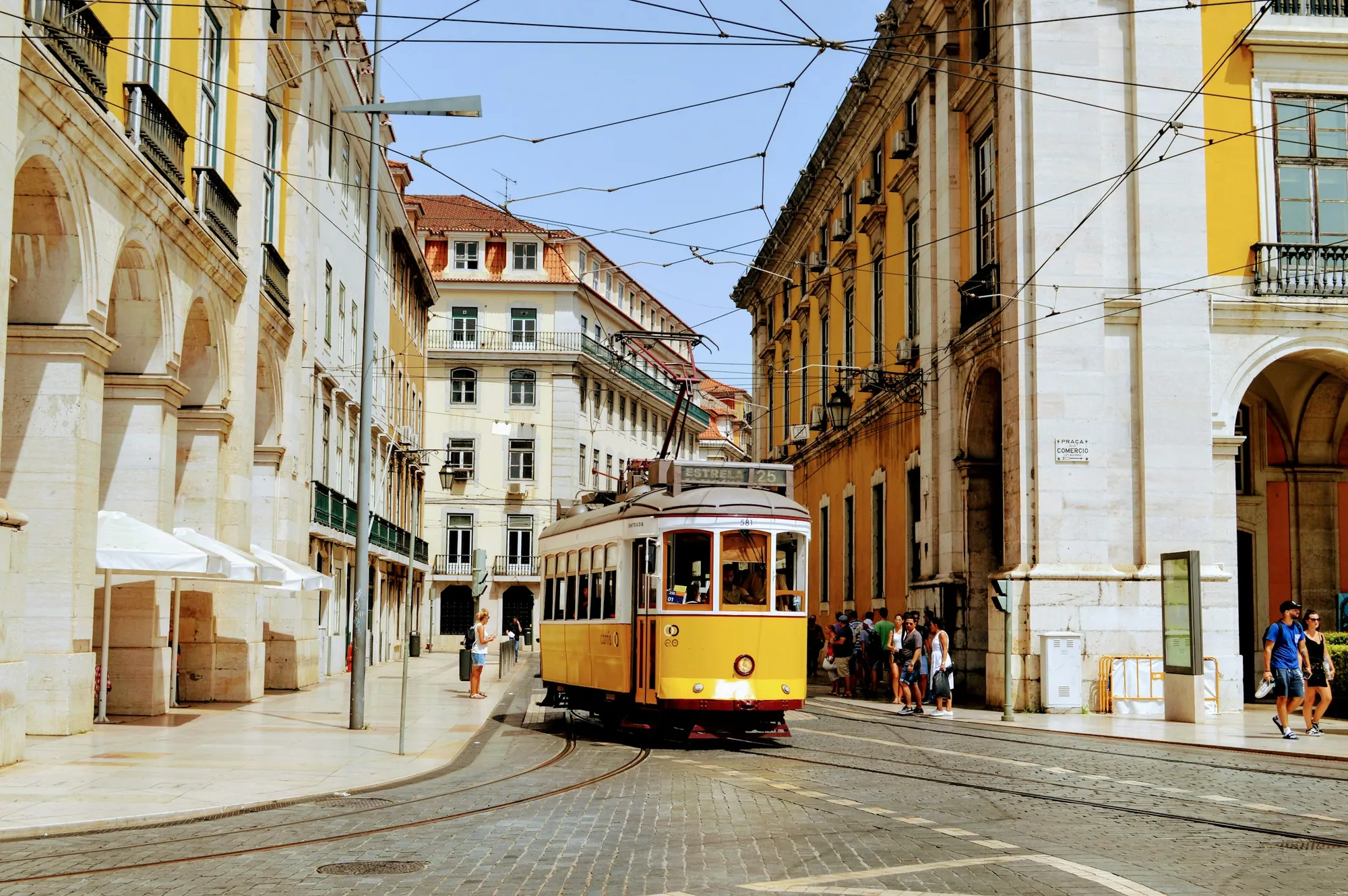 Vue panoramique de Lisbonne au crépuscule avec le tramway jaune, les toits d'Alfama et l'estuaire du Tage en arrière-plan